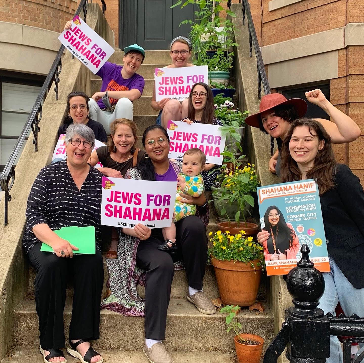 Photo of nine women and a baby sitting on a stoop holding "Jews For Shahana" signs